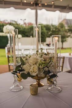 a centerpiece with candles and flowers on a table