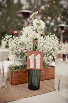 there is a vase with flowers in it and a number sign on the table top