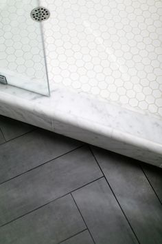 a bathroom with black and white tile flooring next to a walk in shower stall