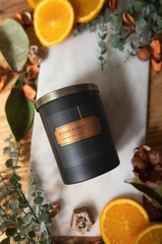 an orange candle sitting on top of a table next to sliced oranges and leaves