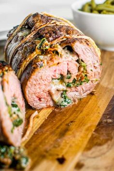 a meatloaf roll cut in half on a wooden cutting board with green beans