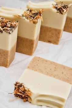 four bars of soap sitting on top of a white sheet covered in brown and white toppings