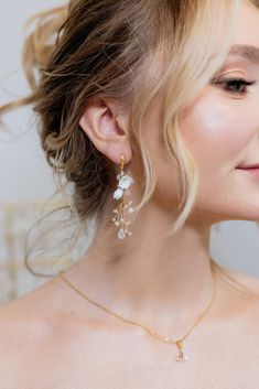 a woman with blonde hair wearing gold and white earrings on her neck, looking off to the side