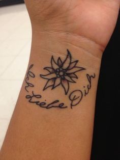 a person with a tattoo on their wrist that says believe and has a flower in the center