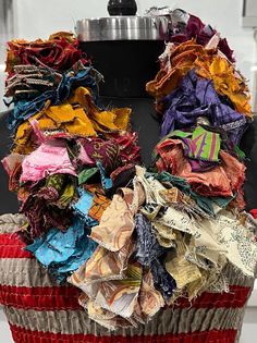 a red and white basket filled with lots of different types of fabric on top of a table