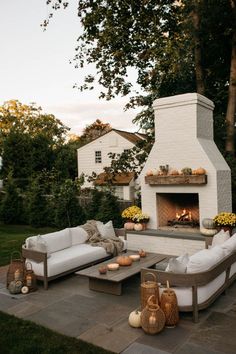 an outdoor fireplace with white couches and tables