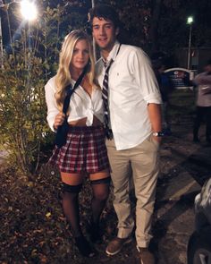 a man and woman standing next to each other in front of some trees at night