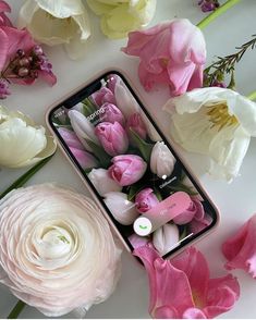 pink and white flowers are laying next to a cell phone