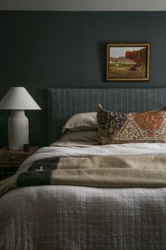 a bed with two lamps on either side of it and a painting above the headboard