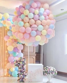 a bunch of balloons are in the air above a cake and flowers on a table