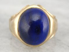 "Suitable for a man or a woman, thanks to it's moderate size, this vintage ring features a high domed, perfectly polished cabochon of deep blue lapis lazuli. Metal: 10K Yellow Gold Gem: Lapis Lazuli Gem Measurements: 14.3 mm x 11.8 mm, Oval Size of Ring: 9 1/4 but can be sized to fit almost any finger (please see our sizing policies for more information). Marks: \"10K\" on inside band W21AQN-P Each piece has been identified and graded by a Graduate Gemologist who has been certified by the Gemolo Classic Yellow Gold Sapphire Ring Oval Cabochon, Classic Oval Cabochon Collectible Jewelry, Classic Formal Cabochon Sapphire Ring, Classic Formal Sapphire Cabochon Ring, Classic Yellow Gold Sapphire Ring With Cabochon, Classic Cabochon Sapphire Ring For Formal Occasions, Formal Domed Signet Ring With Cabochon, Timeless Domed Cabochon Rings, Classic Sapphire Ring Oval Cabochon