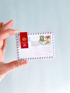 a hand is holding an envelope with a red stamp on it and the letter has been placed inside