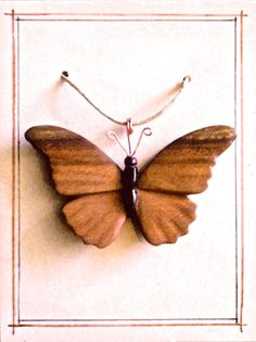 a wooden butterfly mounted to the side of a wall with a string on it's back