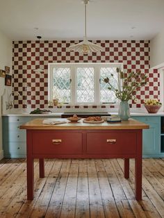 a kitchen with wooden floors and checkered wallpaper on the walls, along with an island