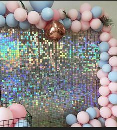 a wall decorated with pink, blue and white balloons in front of a mirror backdrop