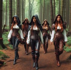 several women dressed in medieval clothing walk down a path through the woods with hoods on