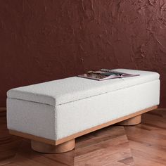 a white bench sitting on top of a hard wood floor next to a red wall