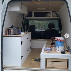 the interior of a van with white cabinets and drawers