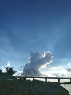 a large cloud is in the sky over a bridge