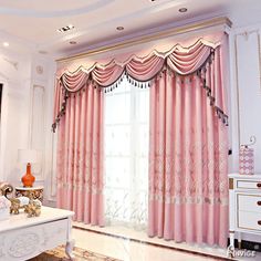 the living room is decorated in pink and white colors with gold trimmings on the windows