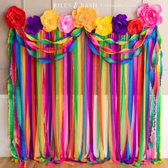 colorful streamers and flowers are hanging on the wall behind a curtain made out of ribbons