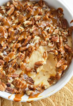 a bowl filled with nuts and cheese on top of a mat next to crackers