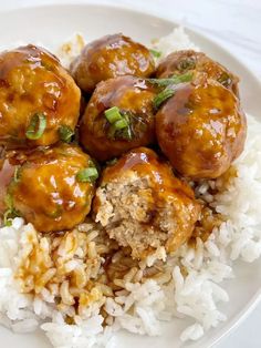 meatballs and rice on a white plate with garnished with green onions are ready to be eaten