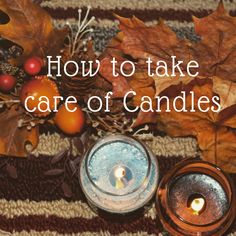 two candles sitting on top of a table next to autumn leaves