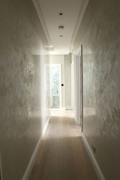 an empty hallway with white walls and wood floors