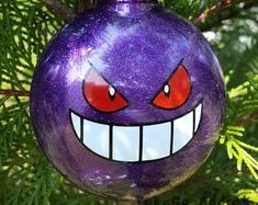 a purple ornament with an evil face on it's side hanging from a tree