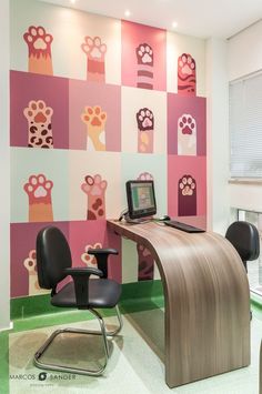 a desk with a computer on top of it in front of a colorful wallpaper