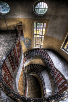 a spiral staircase in an old building with three windows