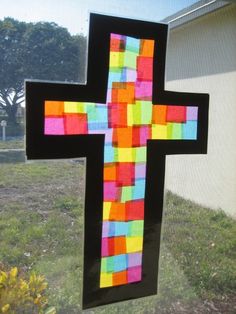 a cross made out of colored paper on a window sill