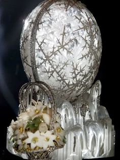 a silver vase with flowers in it sitting on top of a glass stand next to other items