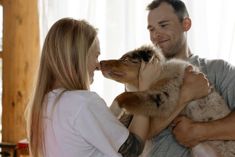 a man and woman are holding two dogs in their arms as they look at each other