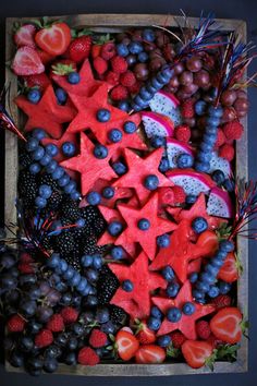 an arrangement of fruits and berries arranged in a star pattern on a wooden tray with blueberries, strawberries, grapes, raspberries, watermelon