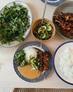 a table topped with plates of food and bowls filled with veggies next to rice