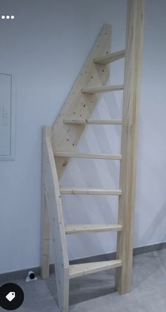 a wooden staircase in a room with white walls and grey flooring on the ground