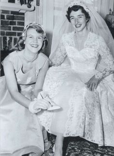 an old photo of two women in wedding dresses sitting on the floor and smiling at the camera