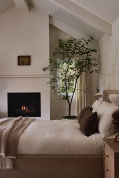 a bedroom with a bed and a fireplace in the corner that has a tree on it