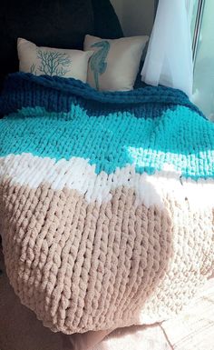 there is a large knitted blanket on top of a bed with pillows and blankets