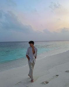 a man is walking on the beach with footprints in the sand and water behind him