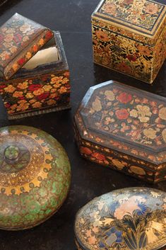 an assortment of decorative boxes sitting on top of a black table next to each other