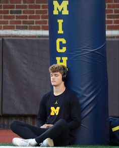 a young man sitting on the ground with headphones in his ears while listening to music