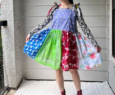 a woman standing in front of a house with bags on her feet and wearing a colorful dress