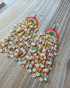 a pair of colorful beaded earrings sitting on top of a wooden table