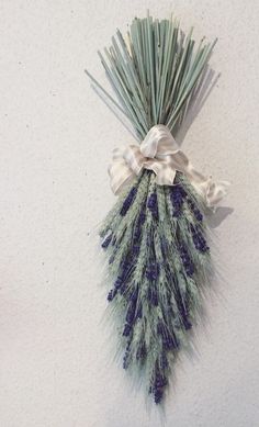 a white and blue flower arrangement hanging on the wall next to it's ribbon