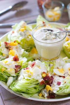 a white plate topped with lettuce covered in dressing and garnished with bacon