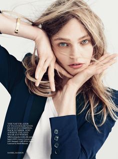 a woman posing with her hands on her head and looking at the camera while wearing a blue blazer