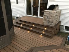 a wooden deck with steps and lights on the bottom level next to a patio door